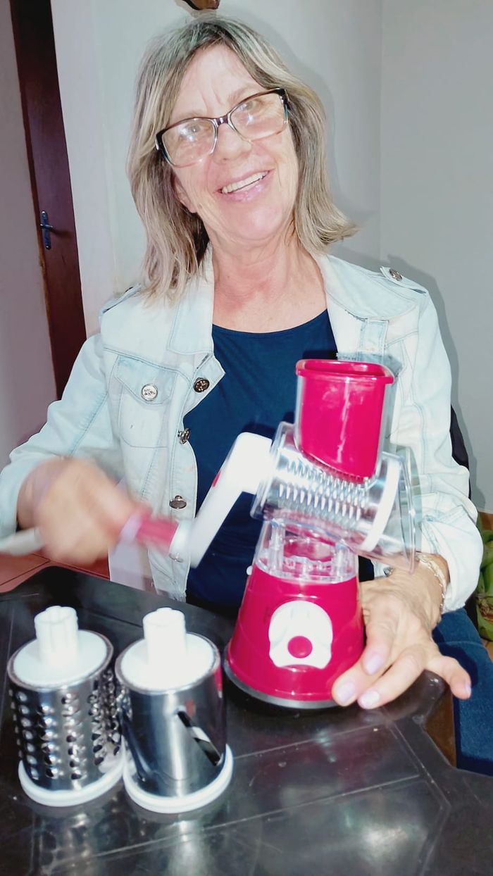 Cleusa mostrando o Ralador 3 em 1 em uso na cozinha
